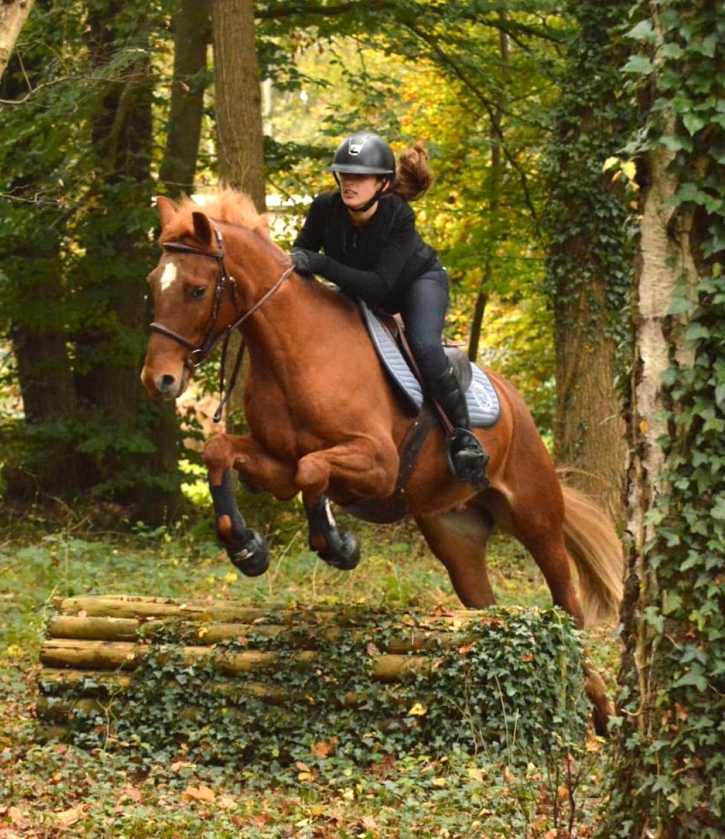 Jeune cavalière montant un cheval en forêt près du centre équestre du Brévedent dans le Pays d’Auge.