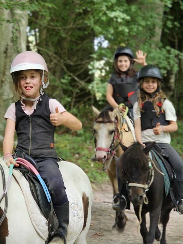 Enfants participant à un stage poney au Brévedent, souriants pendant une séance en extérieur.